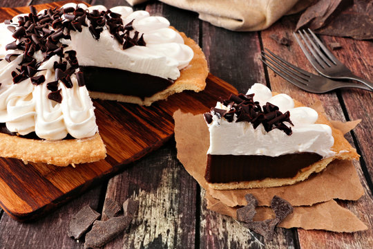 Slice of sweet chocolate cream pie. Close up table scene with a dark wood background.