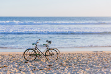 Fototapeta premium Two bikes on beach against ocean waves