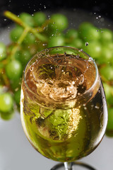 6765805 A glass of white wine on a background of grapes. High speed wine splash. Selective focus