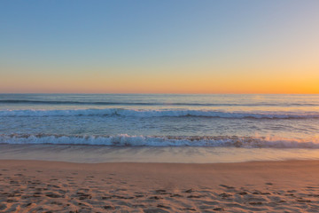 Fototapeta na wymiar Sunset over ocean waves and beach