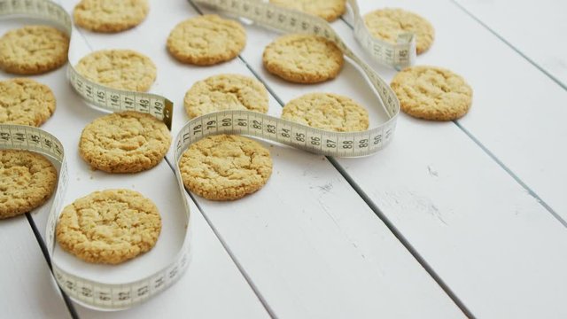Gluten free healthy oatmeal cookies on white rustic wood bacground. Fitness concept with measure tape. Side view with copy space, flat lay.