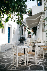 White table and chairs on a white street of Naussa, Paros island, Greece