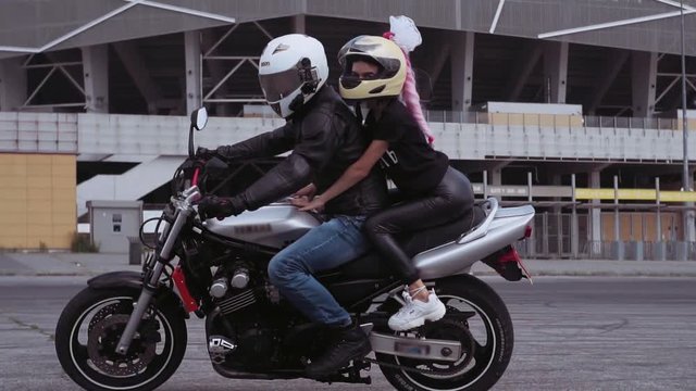 Beautiful Ukrainian woman with amazing pink braid and white bow. Gorgeous Caucasian couple riding motorcycle. Lifestyle. Weekend.