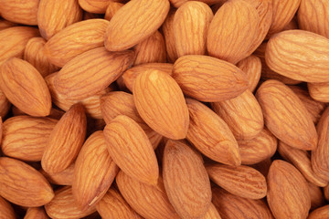 Almonds in wooden dish on white background.