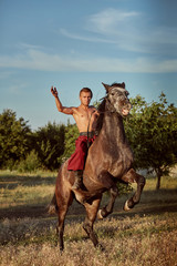 Handsome man cowboy riding on a horse - background of sky and trees