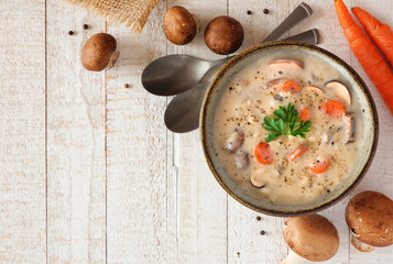 Creamy mushroom soup. Autumn food concept. Top view scene on a white wood background with copy...