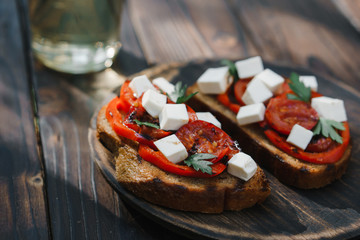 Homemade crostini with grilled tomatoes, bell pepper and feta cheese, natural tasty countryside snack for healthy living, close up