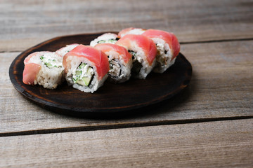 Delicious sushi roll with avocado and cream cheese, covered with tuna slices. Tasty traditional meals, japanese culture, restaurant serving
