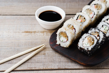 Tasty traditional food, Japanese culture. Sushi rolls with crab meat, cucumber and cream cheese, covered with sesame, restaurant serving