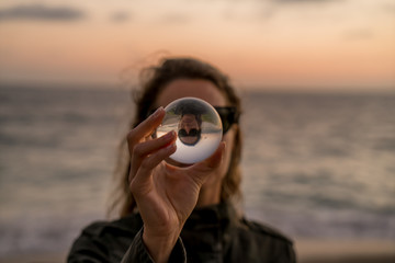Girl holding a lens ball on the beach at sunset time