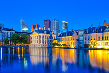 Travel Concepts. Binnenhof Palace of Parliament in The Hague in The Netherlands at Blue Hour. Against Modern Skyscrapers