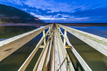 Wooden bridge illuminated with the first artificial lights in order to cross from the land to the...