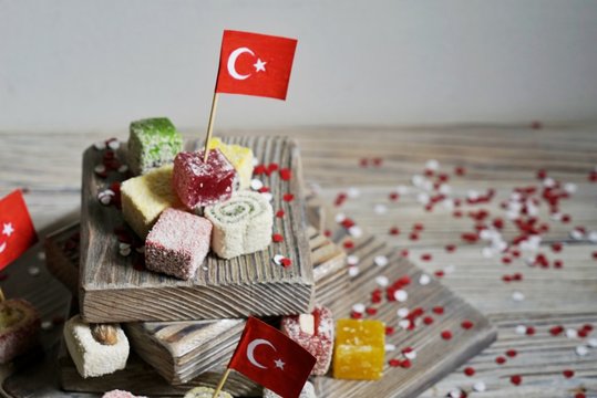 various national Oriental sweets, with paper flags of Turkey, Turkish delight on a wooden white brushed stand and on a white brushed background, horizontal, 