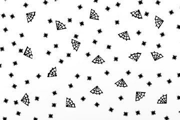 Spiders and spiderweb confetti on the white background. Halloween party concept. Flat-lay, top view.