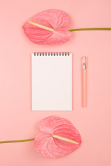 Two pink flamingo flowers, a notepad and a pen. Beautiful stationery concept. Flat-lay, top view. Copy space for your text.