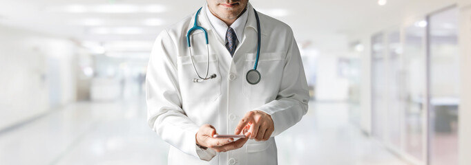Male doctor using mobile phone at hospital.