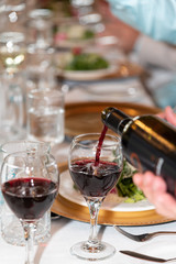 pouring two glasses of red wine on table