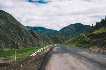 Mountain highway across pass. Asphalt road near mountainside. Amazing colorful highland landscape of majestic nature.