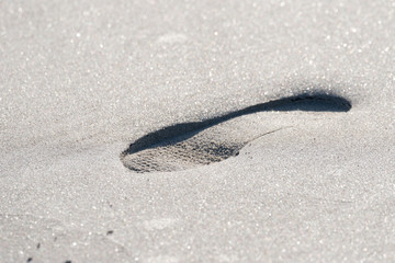 Ein Schuhabdruck im Sand am Strand