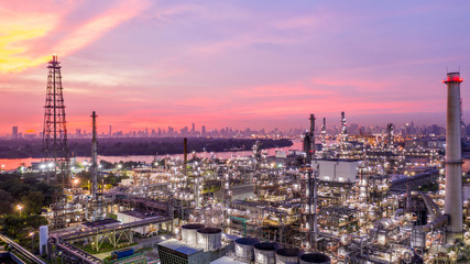 Fototapeta premium Aerial view petrochemical industrial oil refinery at sunset with city background.