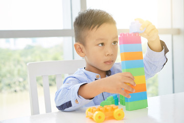 Fototapeta na wymiar Little Vietnamese boy making tower out of plastic cubes