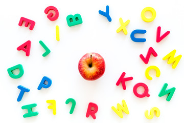 Fototapeta na wymiar Alphabet for kids concept. English letters in disorder near apple on white background top view
