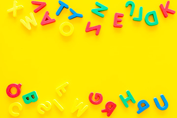 Alphabet for kids concept. English letters in disorder on yellow background top view copy space