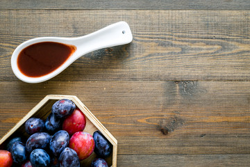 Fresh tkemali sauce. Traditional caucasian, georgian sauce or plum jam in spoon near plums on dark wooden background top view copy space