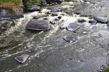 top view of the fast mountain river with rapids, rocks in the middle of the river flow with foam