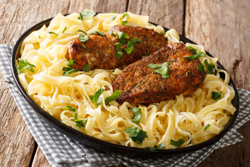 American fried chicken breast lazone with fettuccine pasta in a creamy sauce closeup on a plate. horizontal