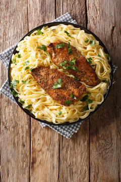 New Orleans chicken Lazone fried with spices and fettuccine pasta in a creamy sauce close-up. Vertical top view