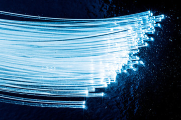 Bundle of optical fibers with lights in the ends. Blue background.