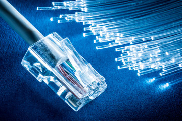 Network cable and optical fibers with lights in the ends at the background.