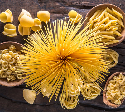 Different pasta types on the wooden table. Top view.