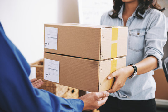 Female delivery service manager giving packages to courier