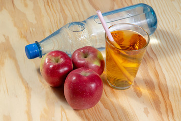 glass of apple spritzer and red apples on wooden background
