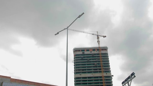 Crane works on the construction site against the background of a high-rise building. Steadicam shot