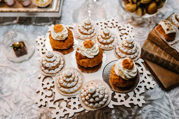 Table with sweets and goodies for the wedding party reception, decorated dessert table. Delicious sweets on candy buffet. Dessert table for a party. cakes, cupcakes.