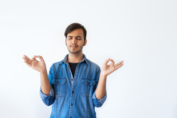 Focused young Indian man holding hands in mudra sign with closed eyes. Portrait of handsome dark...