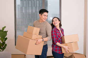 Happy couple staring at each other eyes and carrying boxes in their new house