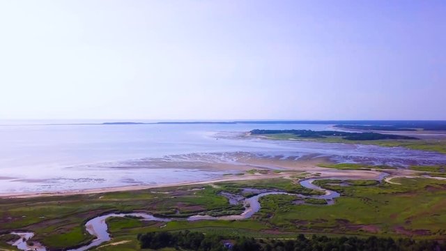 Sunken Meadows on Cape Cod, MA. The marsh and channels of water connect to the bay. The tide is low and much of the beach is freshly exposed. The camera pulls out revealing more of the marsh.