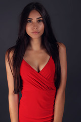 beautiful young woman wearing a red dress on gray