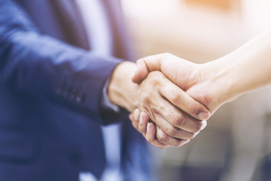 Concept of Negotiating business and handshake Gesturing People Connection Deal. close up hand of business man shaking hands with partner or customer on modern city background,fair play. film tone