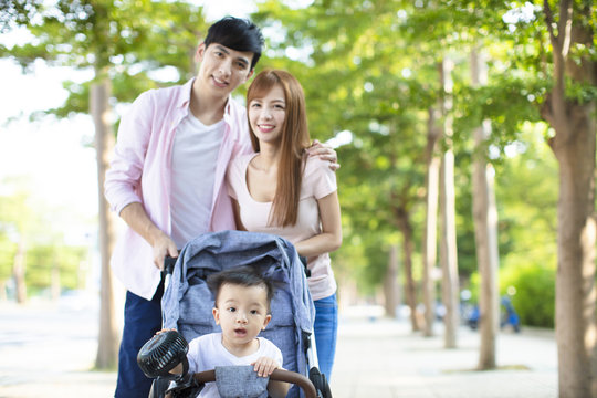 happy family with baby carriage walking in the park