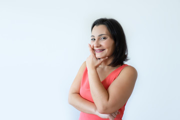 Portrait of happy attractive Caucasian woman holding chin and smiling. Pretty middle aged woman in pink dress coming up with idea. Bright idea concept.