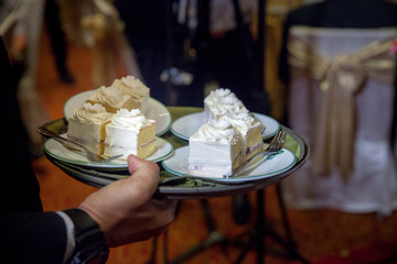 Slice of wedding cakes on dish. Bride and groom giving slice of wedding cake to guest. sign of...
