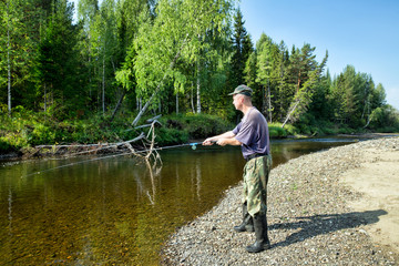 The fisherman catches fish in the river