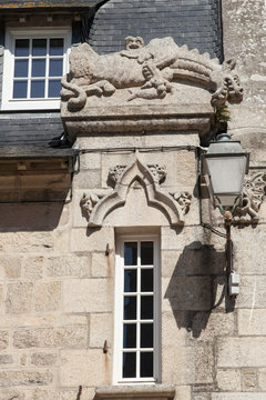 Vieille fenêtre étroite surmontée d'une sculpture de dragon