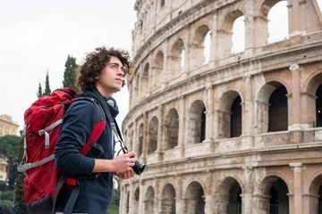 Foto op Canvas Handsome young tourist man with a camera and backpack taking pictures of Colosseum in Rome, Italy. Young tourist taking pictures of Colosseum © Marko Rupena