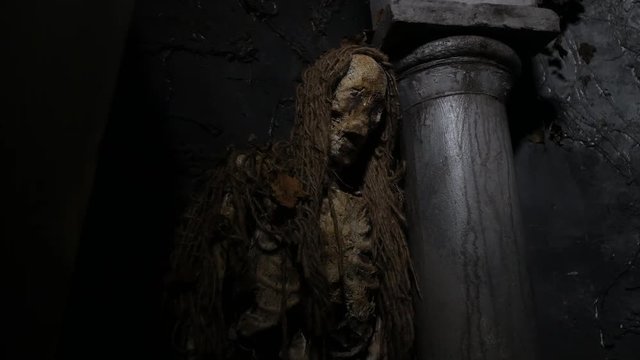 Haunted dead rotting mummy corpse leaning on pillar